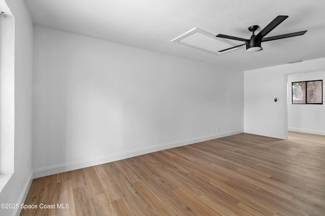 unfurnished room with ceiling fan, light hardwood / wood-style flooring, and a skylight