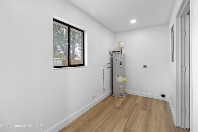 washroom with light hardwood / wood-style floors, electric water heater, and electric dryer hookup