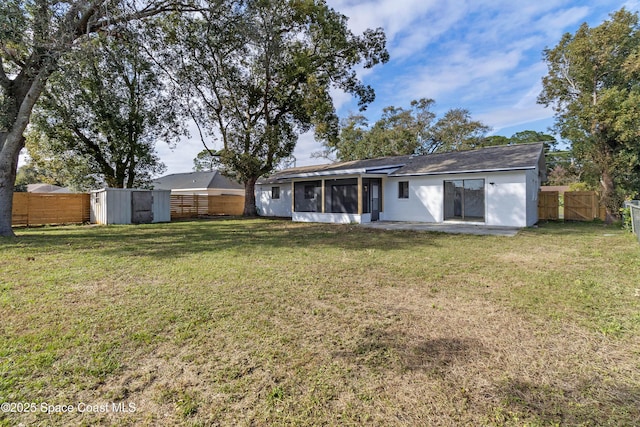 back of house with a storage unit, a patio, a yard, and a sunroom