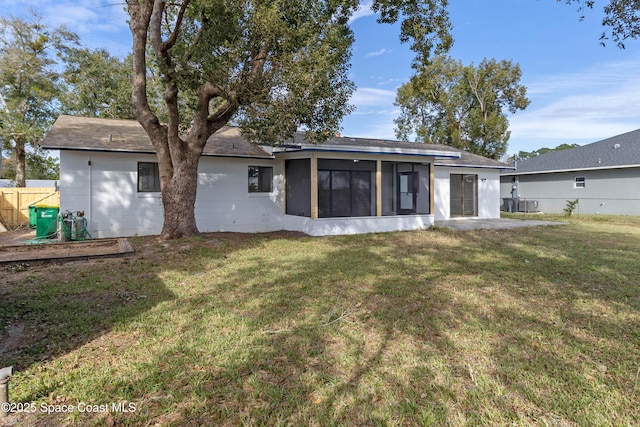 rear view of house featuring central AC unit, a sunroom, and a yard