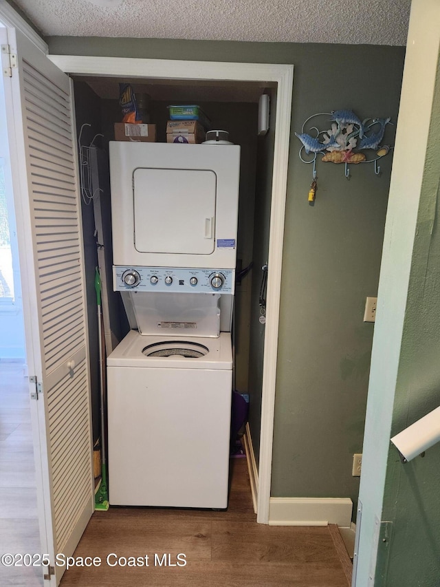 washroom featuring hardwood / wood-style flooring, stacked washer and clothes dryer, and a textured ceiling