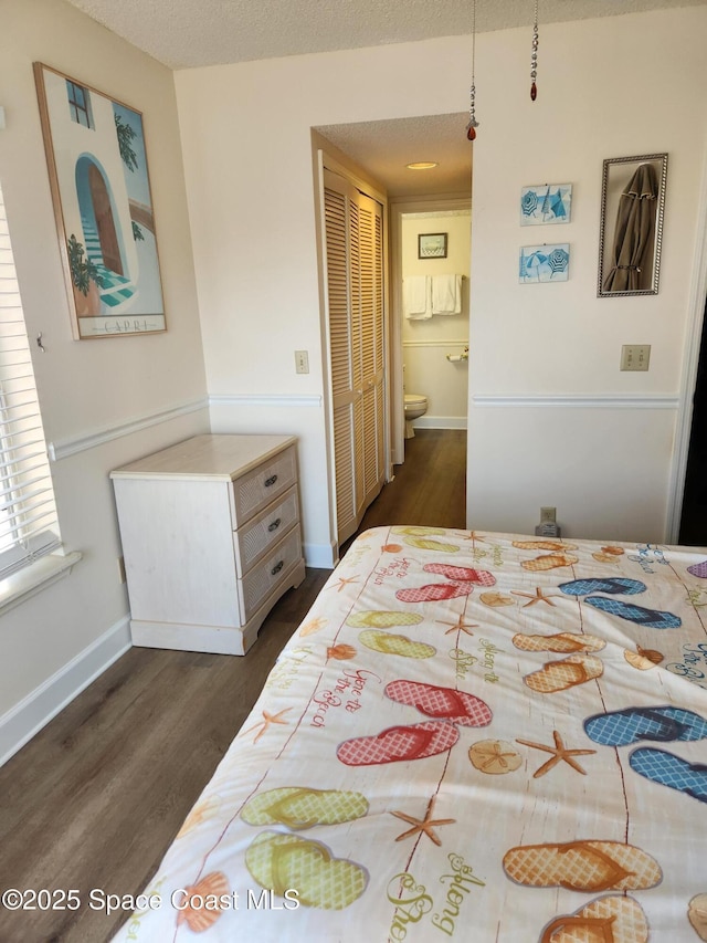 bedroom featuring connected bathroom, a textured ceiling, and dark hardwood / wood-style flooring