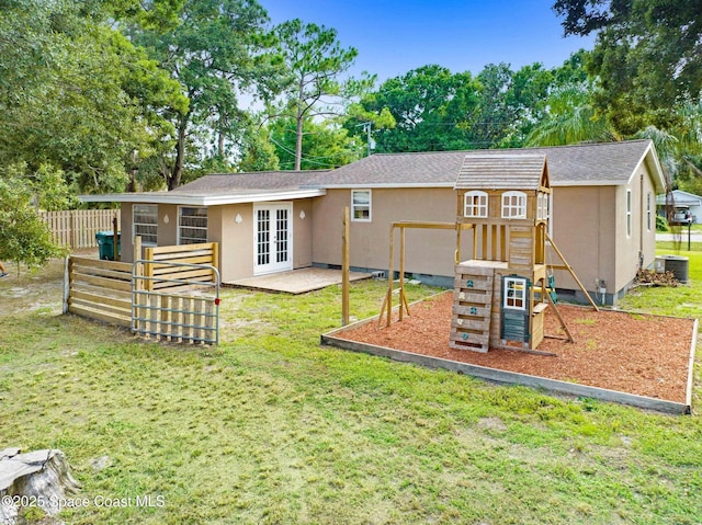 rear view of house with cooling unit, french doors, a yard, and a playground