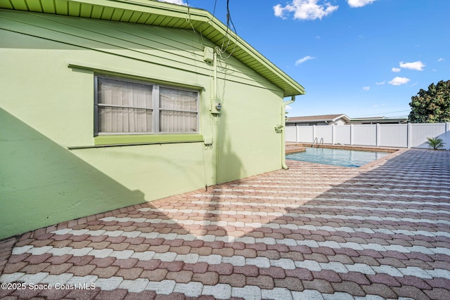 view of side of home with a fenced in pool and a patio