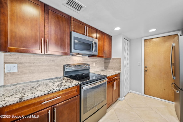 kitchen featuring light stone countertops, light tile patterned floors, decorative backsplash, and appliances with stainless steel finishes