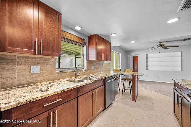 kitchen featuring ceiling fan, light colored carpet, stainless steel dishwasher, sink, and light stone counters