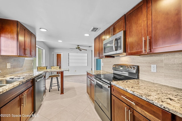 kitchen featuring ceiling fan, sink, light stone countertops, appliances with stainless steel finishes, and light carpet