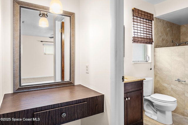 bathroom featuring toilet, vanity, tiled shower, and a healthy amount of sunlight