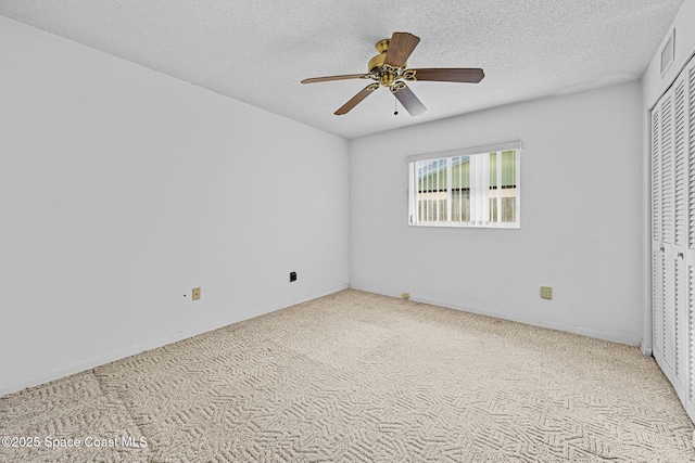 unfurnished bedroom featuring ceiling fan, a textured ceiling, a closet, and light carpet