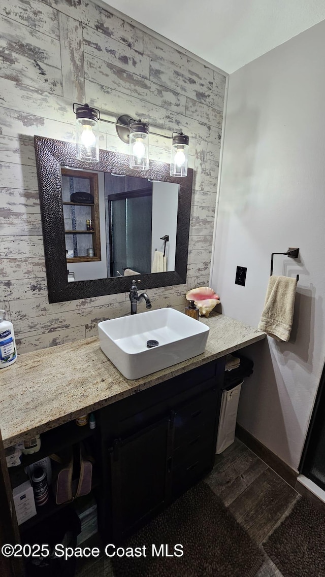 bathroom featuring vanity, wooden walls, and hardwood / wood-style flooring