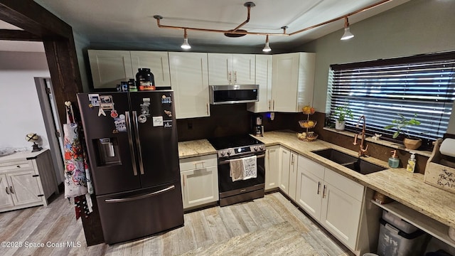 kitchen featuring light stone countertops, white cabinetry, stainless steel appliances, sink, and light wood-type flooring