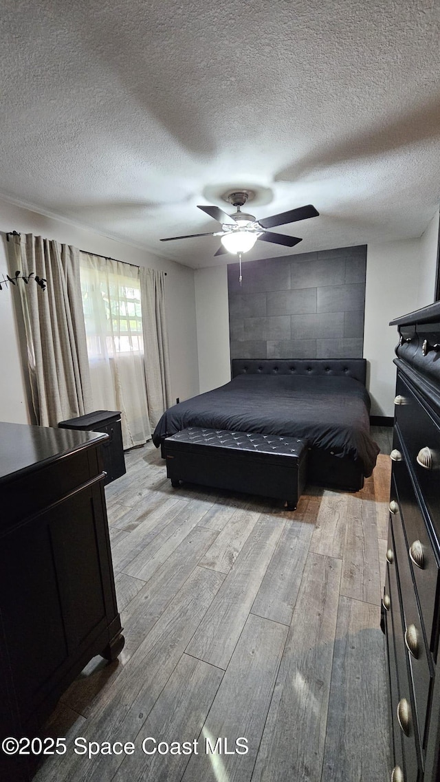 bedroom featuring ceiling fan, a textured ceiling, and light hardwood / wood-style flooring