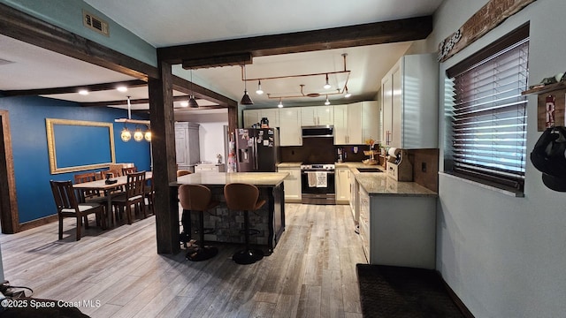 kitchen featuring white cabinetry, ventilation hood, stainless steel appliances, decorative light fixtures, and beamed ceiling