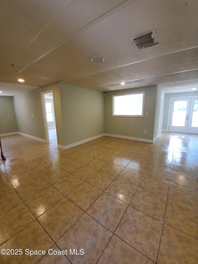 tiled spare room featuring a textured ceiling and a healthy amount of sunlight