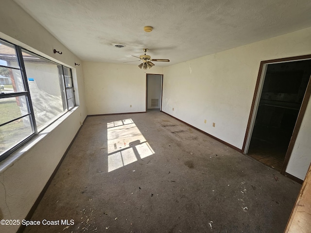 empty room featuring a ceiling fan, baseboards, visible vents, and a textured ceiling