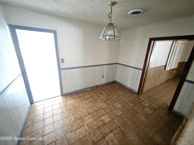 unfurnished room with a wainscoted wall and visible vents