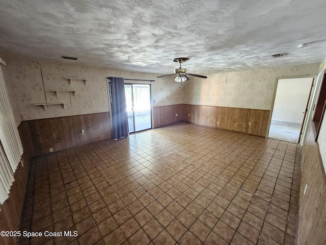 empty room featuring a wainscoted wall, wood walls, and visible vents