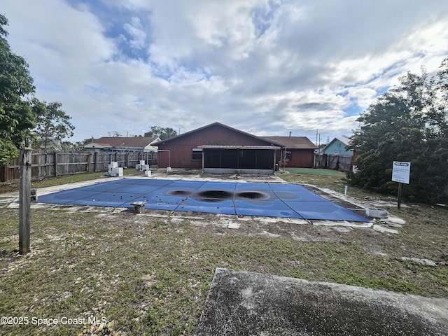 community pool featuring a lawn, a patio area, fence, and a sunroom