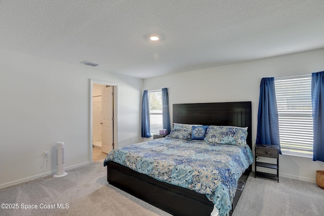 bedroom featuring a textured ceiling, ensuite bathroom, and carpet flooring