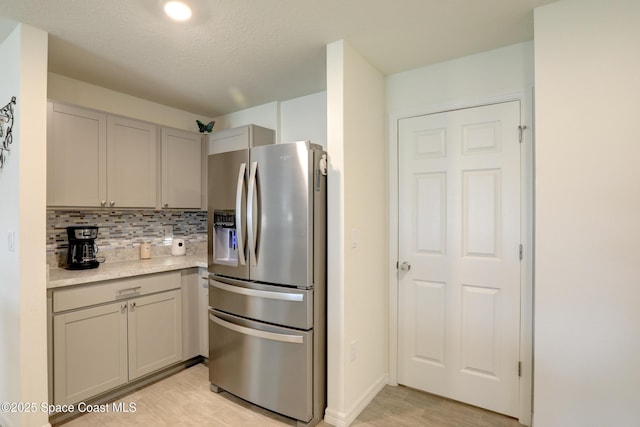 kitchen featuring tasteful backsplash, light wood-type flooring, stainless steel fridge with ice dispenser, and gray cabinets