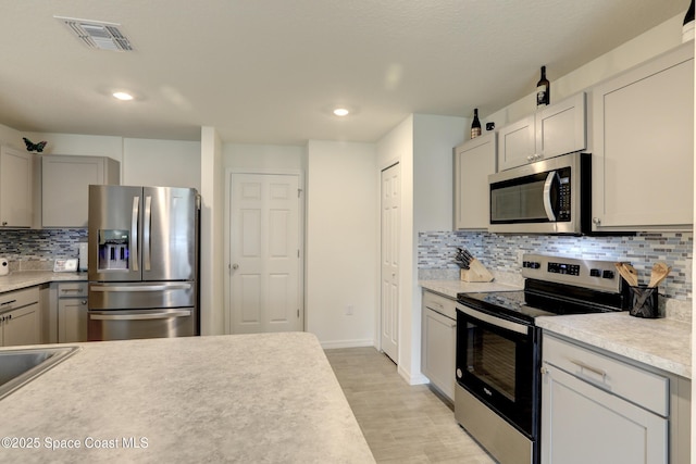 kitchen featuring backsplash, gray cabinets, and stainless steel appliances