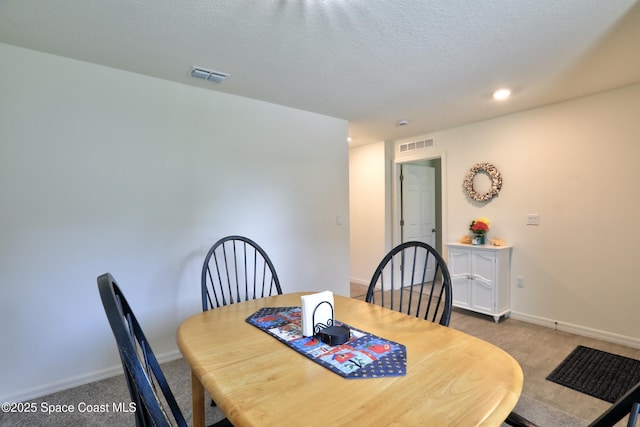 carpeted dining space with a textured ceiling