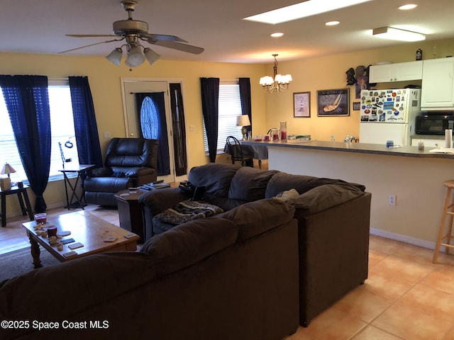 tiled living room featuring ceiling fan with notable chandelier