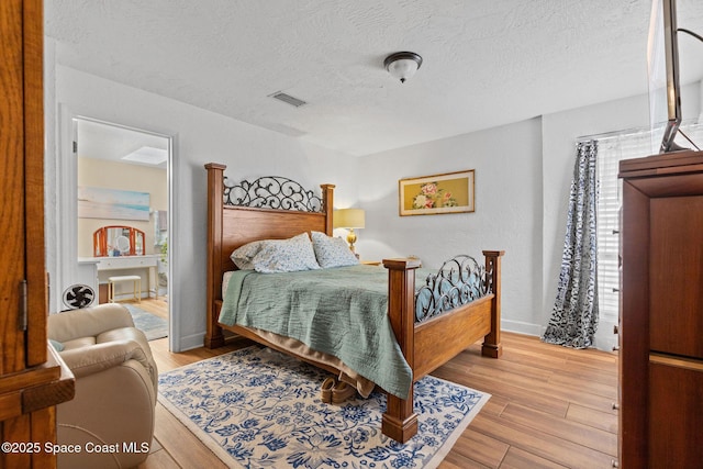 bedroom featuring a textured ceiling and light hardwood / wood-style flooring