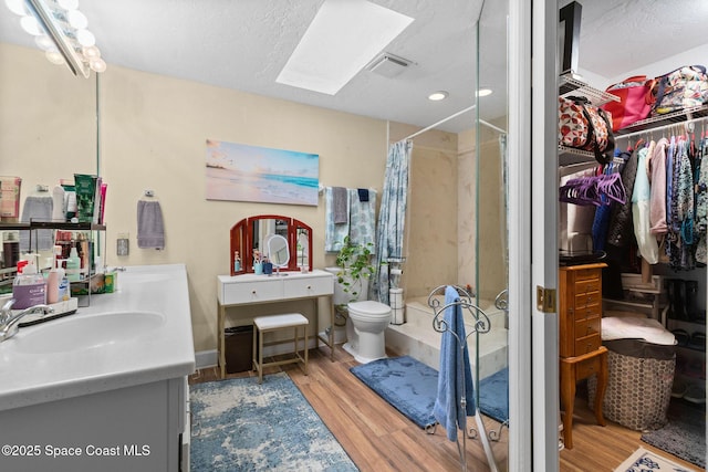 bathroom featuring vanity, a skylight, a textured ceiling, and hardwood / wood-style flooring