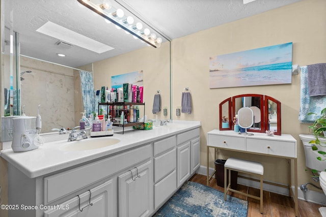 bathroom with a skylight, hardwood / wood-style floors, a shower with shower curtain, a textured ceiling, and vanity