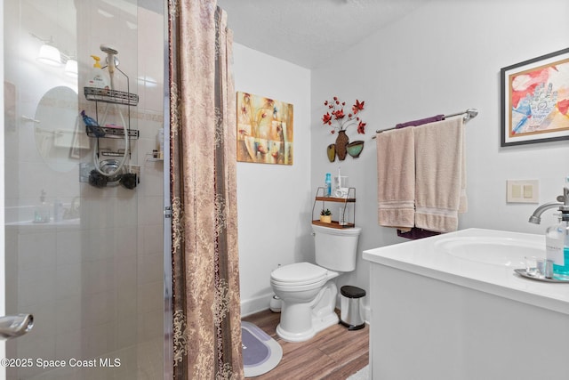 bathroom with toilet, vanity, walk in shower, hardwood / wood-style flooring, and a textured ceiling