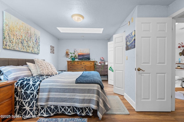 bedroom featuring a textured ceiling, a skylight, and hardwood / wood-style floors