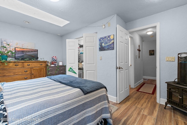 bedroom featuring a textured ceiling, a closet, a skylight, and hardwood / wood-style flooring