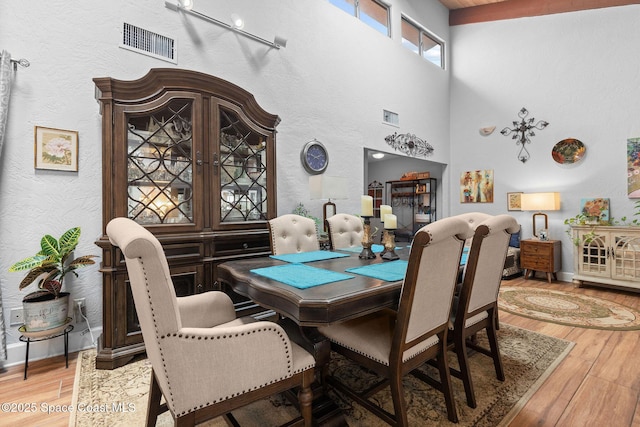 dining area with hardwood / wood-style floors and a towering ceiling