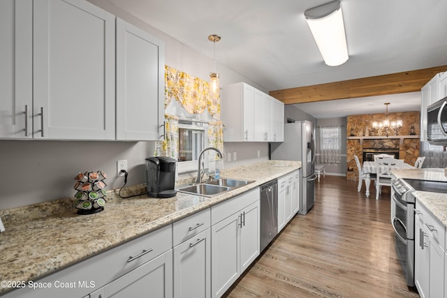 kitchen with white cabinetry, appliances with stainless steel finishes, decorative light fixtures, and sink