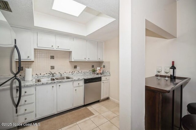 kitchen featuring sink, light tile patterned floors, a tray ceiling, stainless steel appliances, and white cabinets