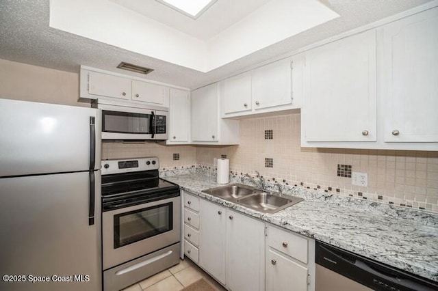 kitchen with tasteful backsplash, white cabinetry, sink, light tile patterned floors, and stainless steel appliances