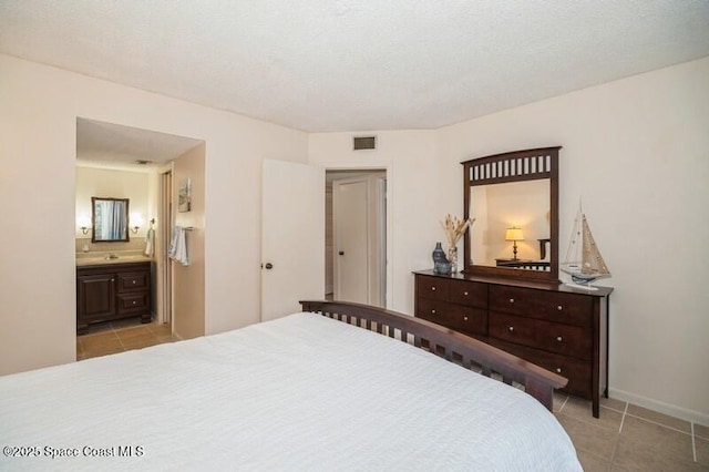 bedroom featuring ensuite bathroom and light tile patterned floors