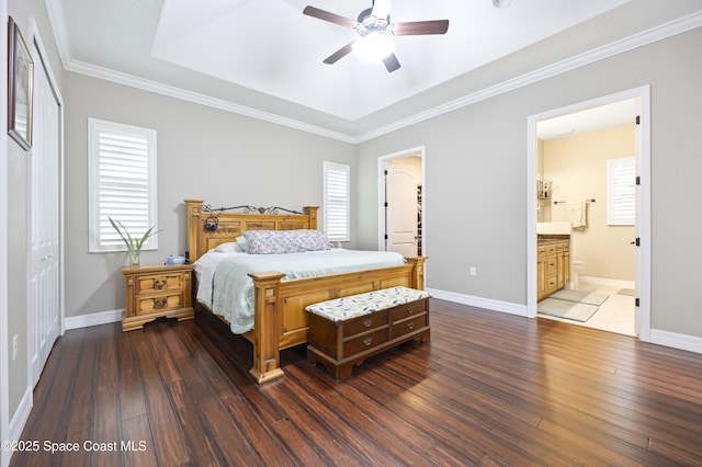 bedroom featuring ensuite bathroom, ornamental molding, dark hardwood / wood-style flooring, a tray ceiling, and ceiling fan