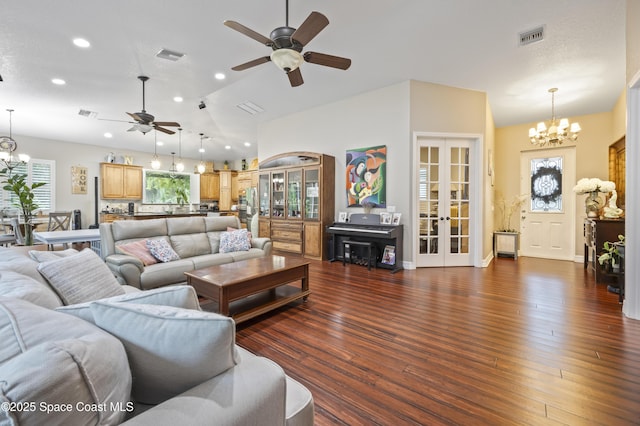 living room with dark hardwood / wood-style flooring, ceiling fan with notable chandelier, vaulted ceiling, and french doors