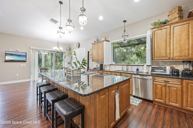 kitchen featuring stainless steel dishwasher, decorative light fixtures, and a kitchen island