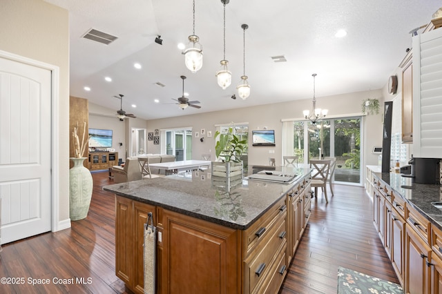 kitchen with gas cooktop, hanging light fixtures, a center island, dark hardwood / wood-style flooring, and dark stone counters