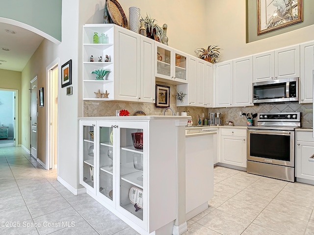 kitchen featuring stainless steel appliances, light tile patterned floors, and white cabinets