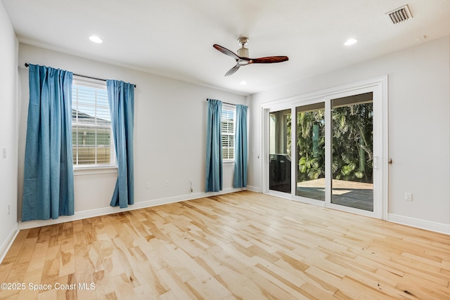 spare room featuring a healthy amount of sunlight, ceiling fan, and light hardwood / wood-style flooring