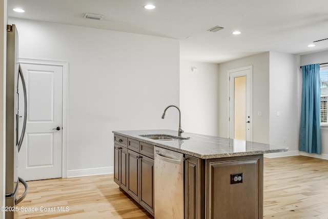 kitchen with appliances with stainless steel finishes, sink, a center island with sink, and light wood-type flooring