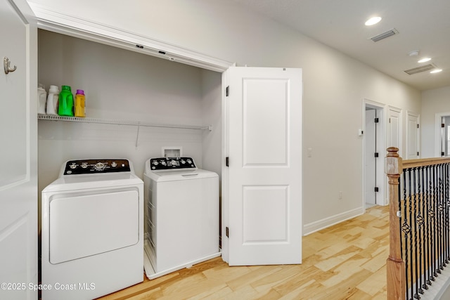 clothes washing area featuring independent washer and dryer and light hardwood / wood-style floors