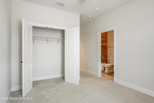 unfurnished bedroom featuring connected bathroom, light carpet, and a closet