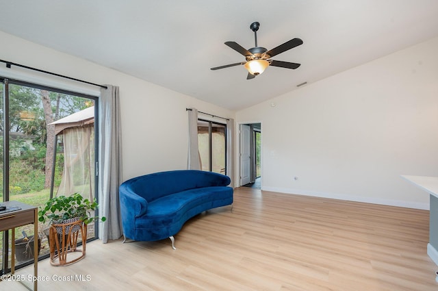 living area with ceiling fan, lofted ceiling, and light wood-type flooring