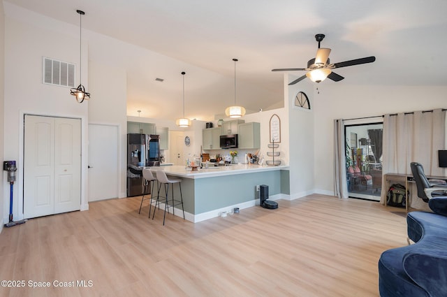 kitchen with a kitchen bar, decorative light fixtures, light hardwood / wood-style flooring, appliances with stainless steel finishes, and ceiling fan