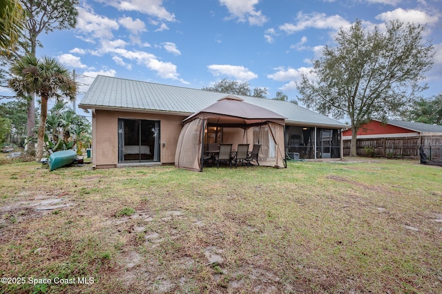 back of property with a sunroom and a lawn